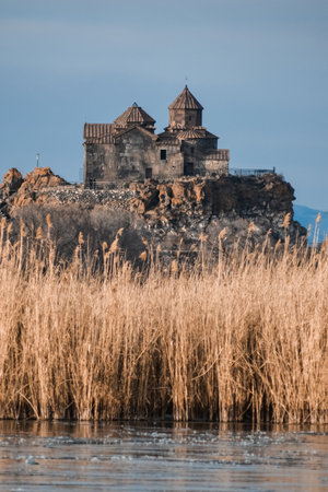 Armenian church in Lake Sevan. Monastery on the river bank. Winter landscape with temple and lakeの写真素材
