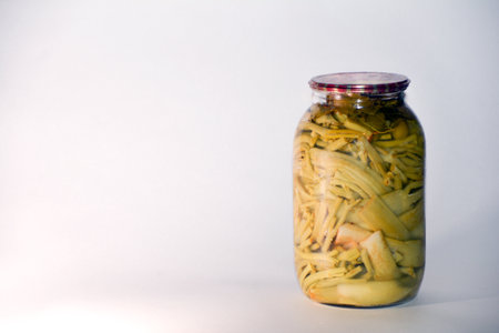 Pickled mushrooms in a glass jar on a white background.の写真素材