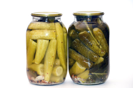 Two glass jars with pickled cucumbers on a white background.の写真素材