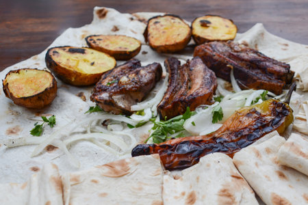Grilled meat with vegetables and pita bread on a wooden tableの写真素材