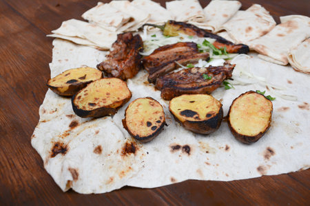 Grilled meat with vegetables and flatbread on a wooden tableの写真素材