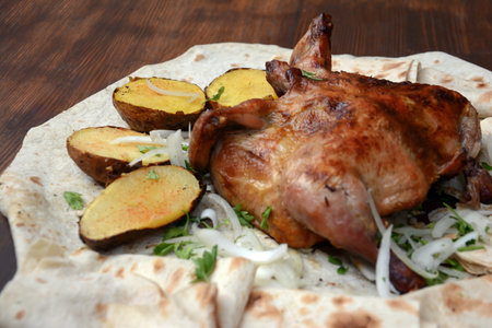 Roasted quail with potatoes and onion on a pita breadの写真素材