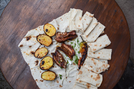 Tortilla with grilled meat and vegetables on wooden board, top viewの写真素材