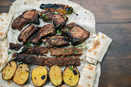 Grilled lamb ribs with grilled vegetables and pita bread on wooden tableの写真素材