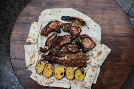 Grilled meat, vegetables and bread on a wooden boardの写真素材