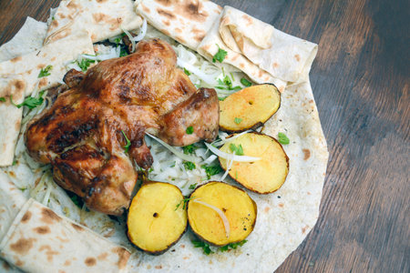 Baked chicken with potatoes and herbs on a pita bread.の写真素材