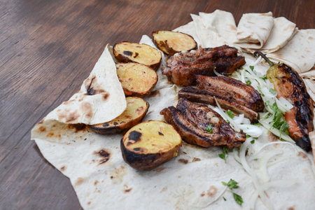 Grilled meat with vegetables and pita bread on a wooden backgroundの写真素材