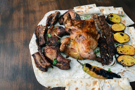 Grilled chicken with baked potatoes and pita bread on wooden tableの写真素材