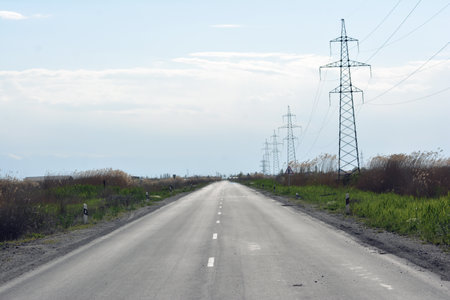 Country road with high-voltage lines on the background of blue skyの写真素材
