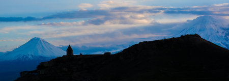 Panorama of a mountain with a church at sunsetの写真素材