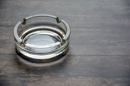 A glass ashtray on a wooden table. Selective focus.の写真素材