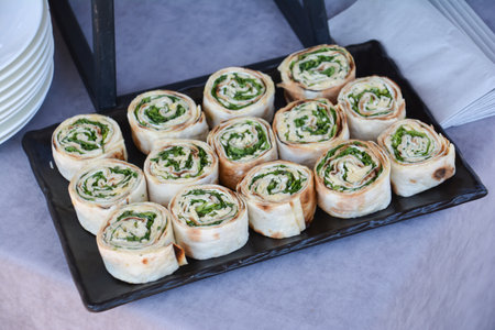 Rolls with cheese and herbs on a black tray in a restaurantの写真素材