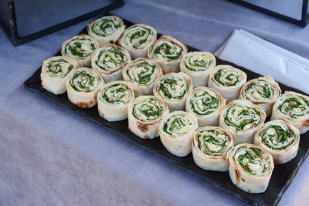 Rolls of puff pastry with spinach and cream cheese on a trayの写真素材