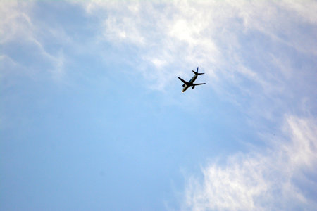 Airplane in the blue sky with white clouds, flying in the air