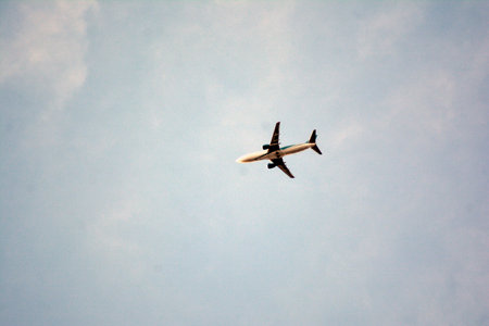 Airplane flying in the blue sky on a sunny summer day.