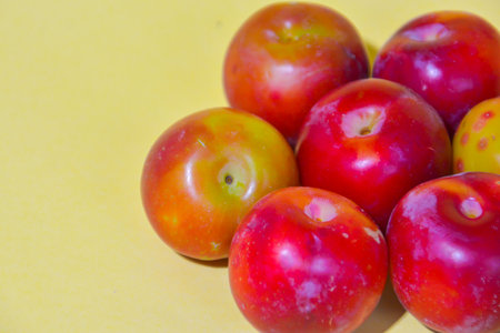 Ripe plums on a yellow background, closeup of photoの写真素材