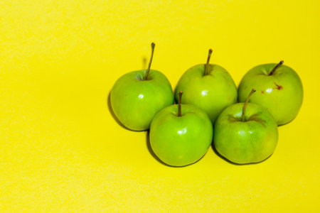 Green apples on a yellow background. Healthy food concept. Copy space.の写真素材
