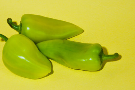 green peppers on a yellow background, close-up, vertical photo