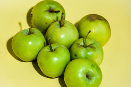 Green apples on a yellow background. The concept of healthy eating.