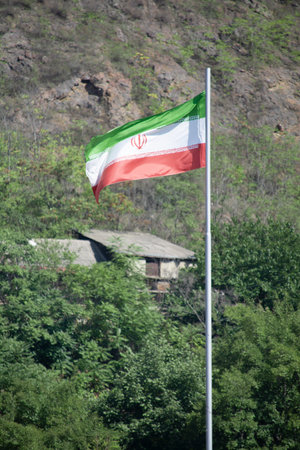 National flag of the Republic of Iran waving in the wind on the background of the mountainsの写真素材