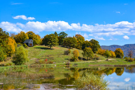 Beautiful autumn landscape with lake, forest and blue sky with cloudsの写真素材