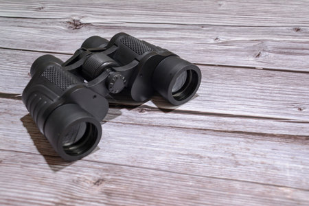 Black binoculars on a wooden background. View from above.の写真素材