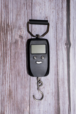 Electric hand scale. A black scale on a wooden table. Electric scale with buttonsの写真素材