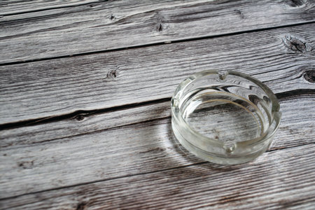 Glass ashtray on old wooden table. Selective focus.の写真素材