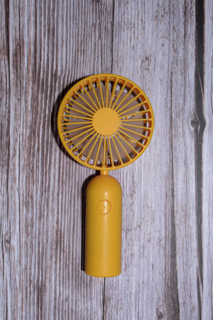 Yellow electric fan on a wooden background. Top view. Copy space.の写真素材