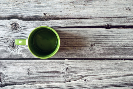 Green cup of coffee on wooden table. Top view with copy spaceの写真素材
