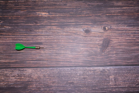 Green dart on a wooden background. Business concept. Top view.