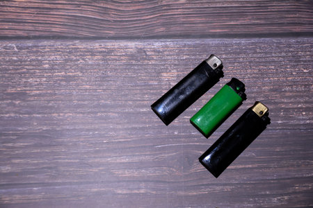 Green and black lighters on a dark wooden background. Top view.