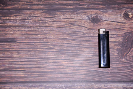 Black lighter on a wooden background. Top view. Copy space.