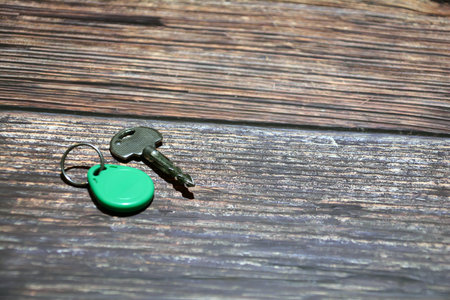 Key with green keychain on a wooden background. Selective focus.