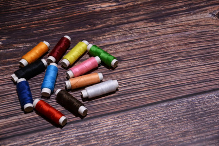 Spools of multicolored thread for sewing on a wooden backgroundの写真素材