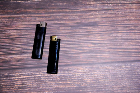 Two black lighters on wooden background. Top view with copy space.の写真素材
