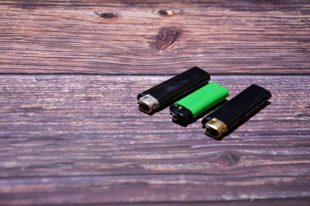 Green and black lighters on a wooden background, close-up.の写真素材