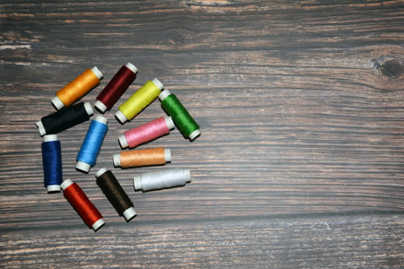 Multicolored sewing threads on the table. Sewing threads in a black case on a wooden background.の写真素材