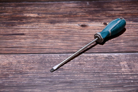 Screwdriver with a plastic handle on a dark wooden background.の写真素材