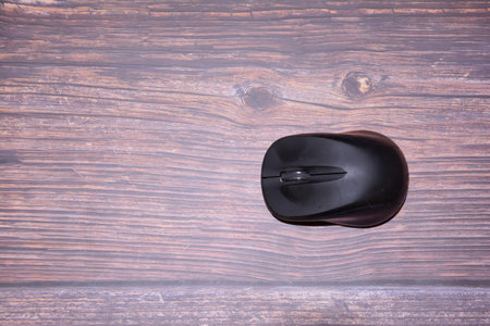 Black computer mouse on wooden background. Top view. Copy space.の写真素材