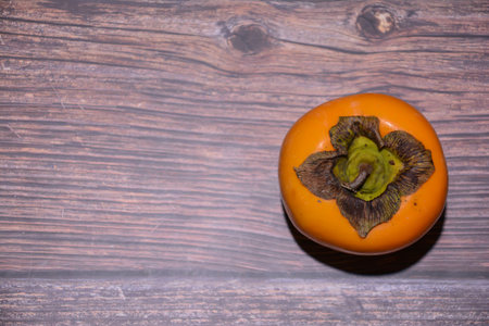 Ripe persimmon fruit on wooden background. Top view.の写真素材