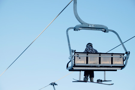 Snowboarder sitting on the chairliftの写真素材