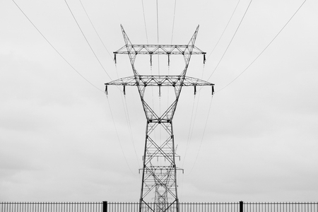 Electricity poles and wires and fence in front.の写真素材