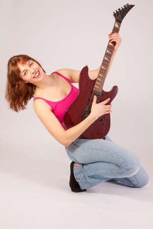 A beautiful young woman is playing a guitarの写真素材