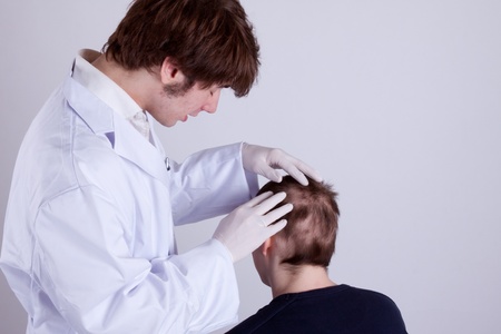 A doctor examines the head of a young manの写真素材