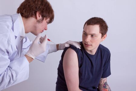 A young man gets an injection from a doctorの写真素材