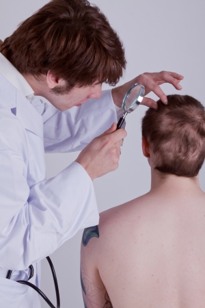 A doctor examines the skin of a patient with a magnifierの写真素材