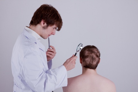 A doctor examines the skin of a patient with a magnifierの写真素材