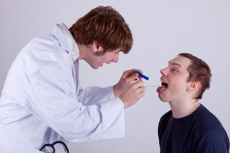 A doctor examines the throat of a young manの写真素材