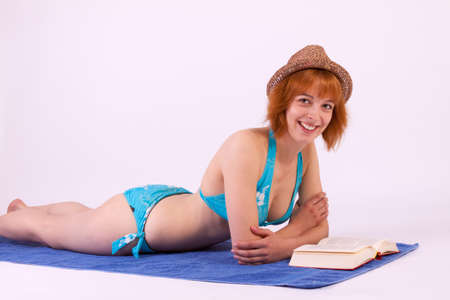 A young beautiful woman in a bikini reading a bookの写真素材
